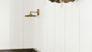 A DIY batten wall behind brass vintage sconces above a green banquette bench