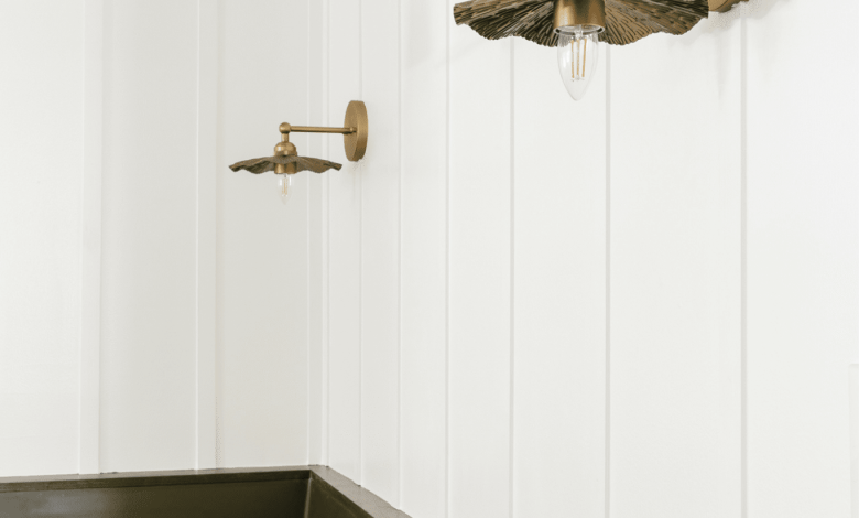 A DIY batten wall behind brass vintage sconces above a green banquette bench