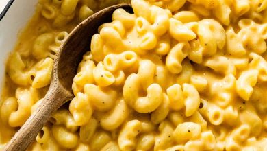 A large pot of cottage cheese mac and cheese with a wooden serving spoon.