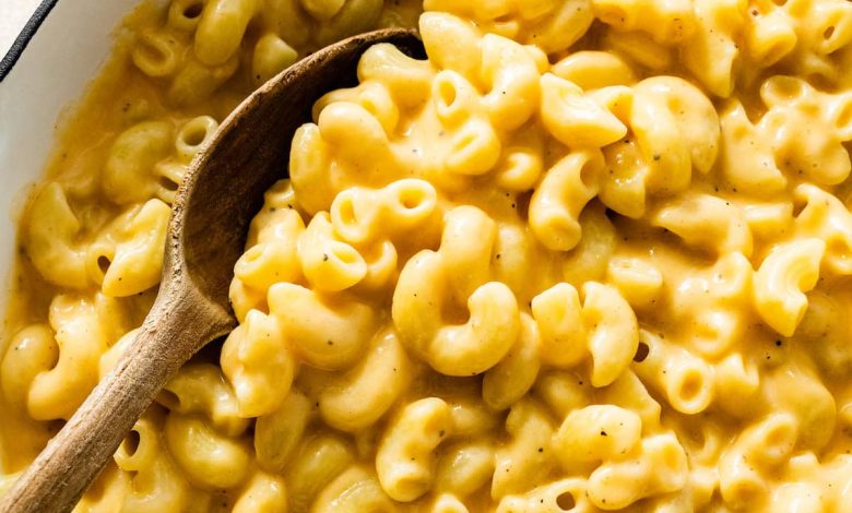 A large pot of cottage cheese mac and cheese with a wooden serving spoon.