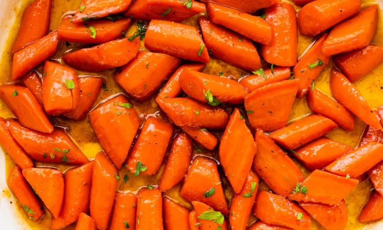 Glazed carrots cooked in a large pot and topped with fresh thyme.