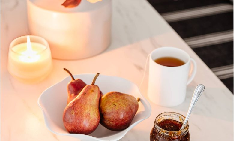 white ruffled bowl on a dining table with pears and vase of fall branches