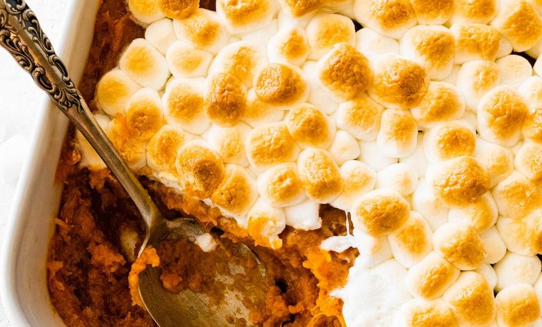 Sweet potato casserole in a square baking dish with a portion missing in the corner where a metal spoon is.