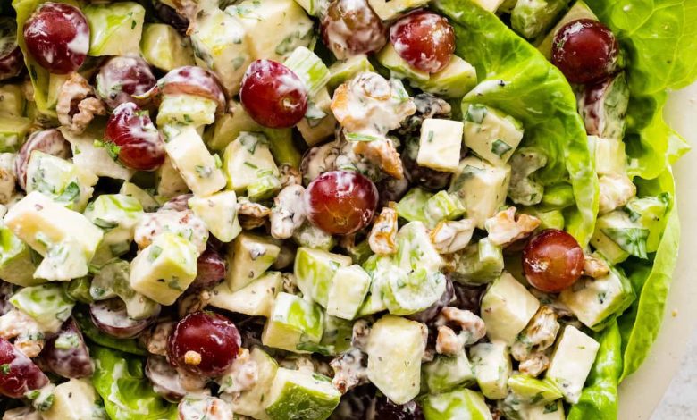 A Waldorf salad with sliced apples and grapes served on a bed of lettuce.