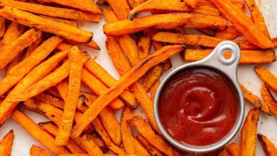 Sweet potato fries spread out near a small container of ketchup.