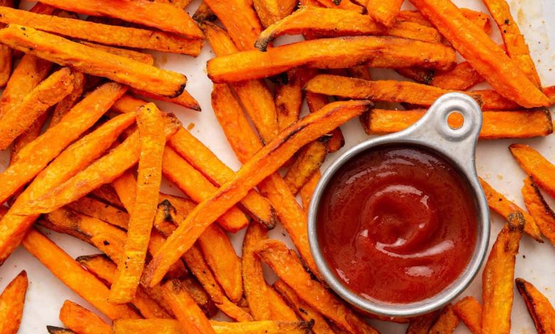 Sweet potato fries spread out near a small container of ketchup.