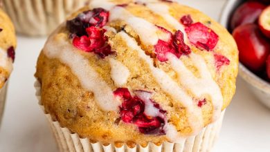 A cranberry orange muffin topped with a drizzle of an almond milk based glaze.