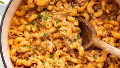 Healthy hamburger helper garnished with fresh herbs, in a large pot with a wooden serving spoon.