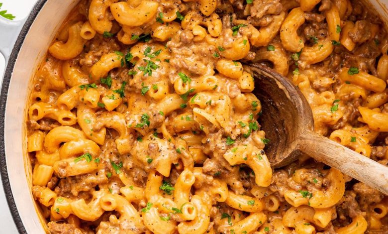 Healthy hamburger helper garnished with fresh herbs, in a large pot with a wooden serving spoon.