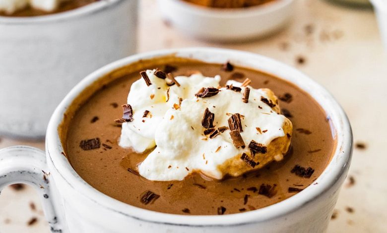 Protein hot chocolate in a white ceramic mug topped with whip cream and shaved chocolate.