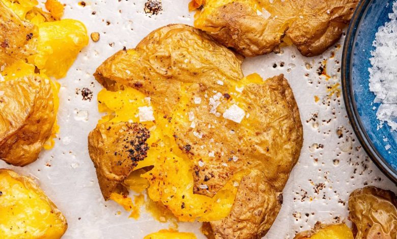 Seasoned and salted smashed potatoes on a baking tray.