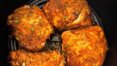 Four bone-in chicken thighs cooked in the basket of an air fryer topped with fresh parsley.