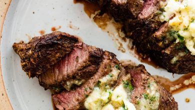 Two filet mignon pieces sliced on a white plate topped with garlic butter.