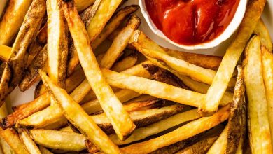 A plate of air fryer french fries with a small container of ketchup on the side.