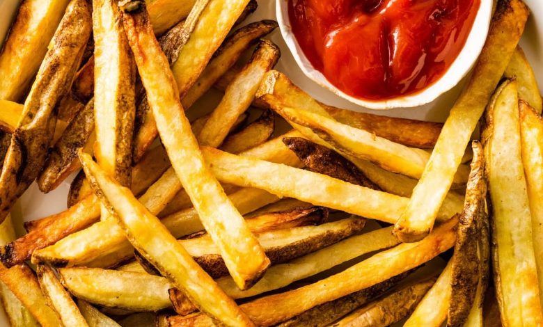 A plate of air fryer french fries with a small container of ketchup on the side.