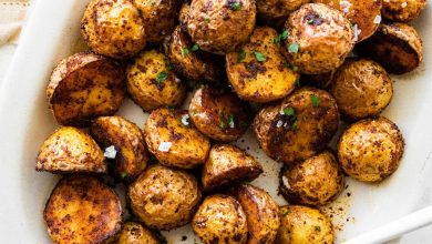 Crispy air fryer potatoes on a white plate garnished with fresh herbs and flaky sea salt.