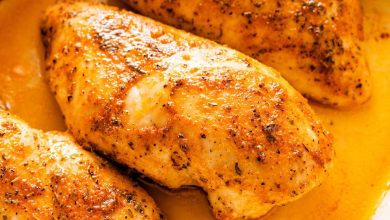 Four baked chicken breasts in a large baking dish.