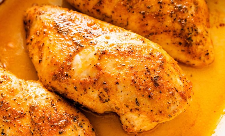 Four baked chicken breasts in a large baking dish.