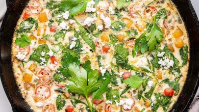 An egg white frittata in a cast iron skillet. The frittata is garnished with fresh herbs and feta cheese.