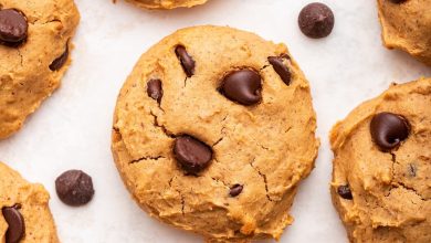 Multiple chocolate chip protein cookies are spread out on a countertop.