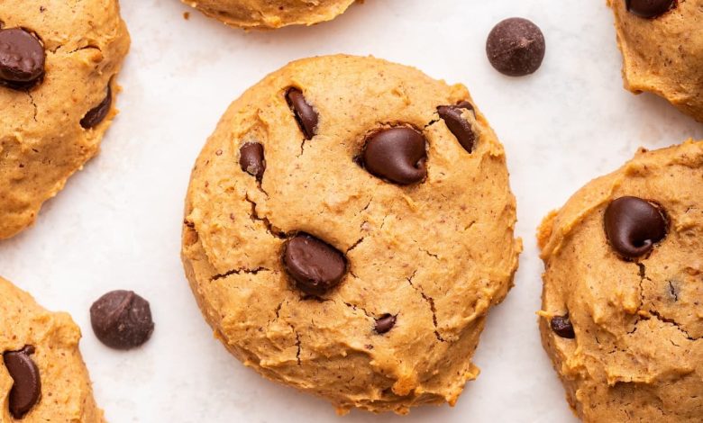 Multiple chocolate chip protein cookies are spread out on a countertop.