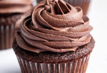 Three chocolate cupcakes topped with chocolate buttercream frosting.