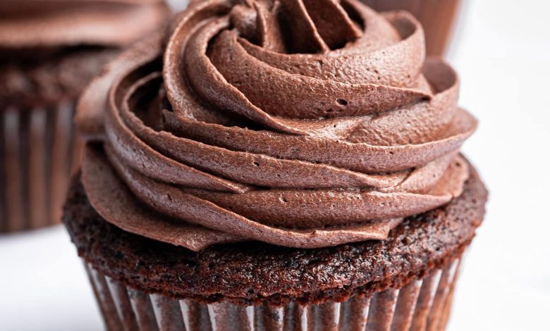 Three chocolate cupcakes topped with chocolate buttercream frosting.