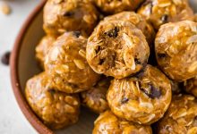 No bake energy balls piled in a bowl, with one ball showing a bite taken out of it.