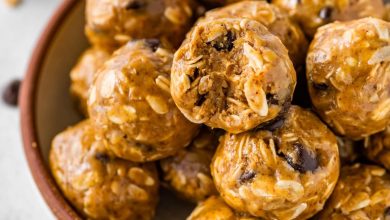 No bake energy balls piled in a bowl, with one ball showing a bite taken out of it.