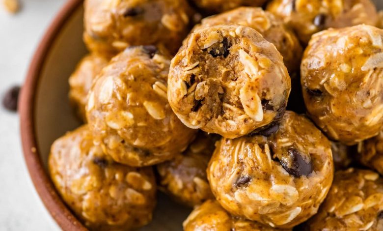 No bake energy balls piled in a bowl, with one ball showing a bite taken out of it.