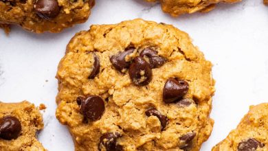 Multiple peanut butter oatmeal cookies with chocolate chips spread out on a table. One of the cookies has a bite taken out of it.