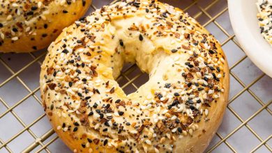 Four everything bagels on a gold cooling rack.