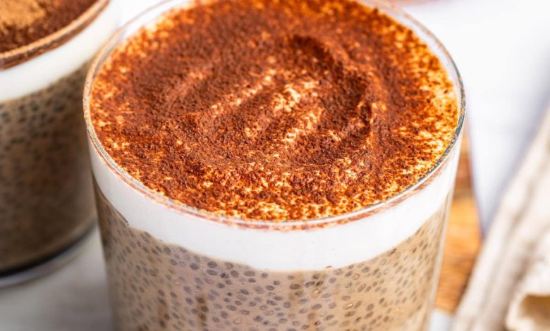 A glass cup of tiramisu chia pudding topped with cocoa powder.