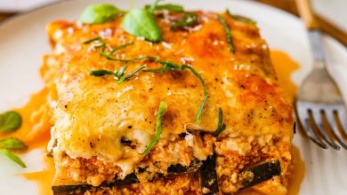 A serving of vegetarian tofu lasagna made with zucchini noodles on a white plate with a fork.