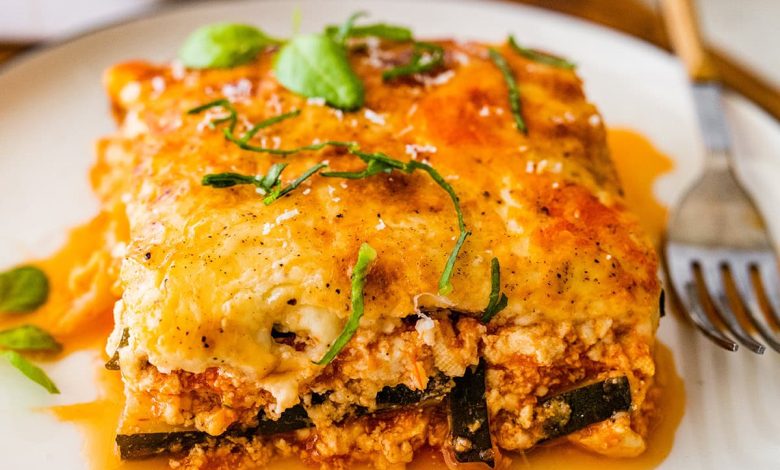 A serving of vegetarian tofu lasagna made with zucchini noodles on a white plate with a fork.