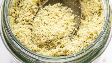 A vegan parmesan cheese made with hemp seeds in a glass mason jar with a metal spoon.