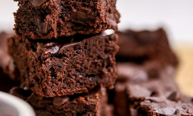 Three protein brownies stacked on top of one another. The top brownie has a bite taken out of it.