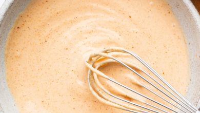 Homemade yum yum sauce in a small ceramic bowl with a silver whisk.