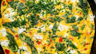 A cooked frittata in a white cast iron skillet topped with fresh parsley. There is a kitchen towel covering the skillet handle.