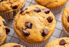 Kodiak cake muffins with chocolate chips on top, cooling on a wire rack.