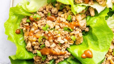 Ground chicken lettuce wraps served on a plate with a peanut sauce drizzle and fresh green onions.
