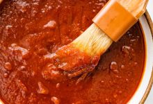 A bowl filled with homemade BBQ sauce with a small brush in the sauce.