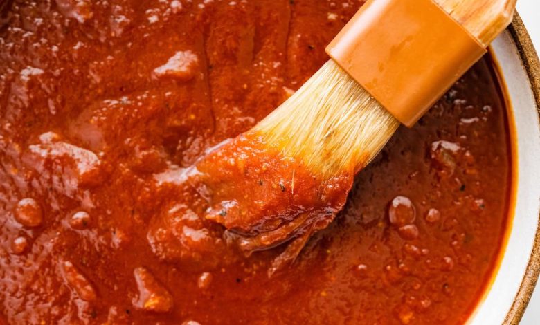 A bowl filled with homemade BBQ sauce with a small brush in the sauce.