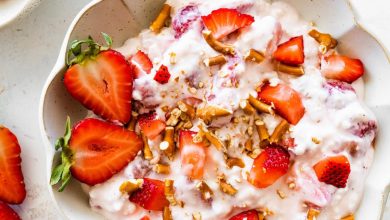 A bowl of strawberry pretzel salad topped with strawberries and crushed pretzels.