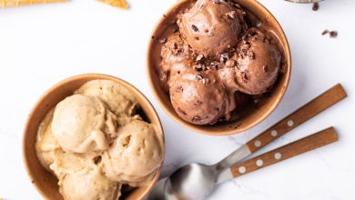 Two bowls of protein ice cream-one is chocolate and one is vanilla. There are two spoons next to the bowls.