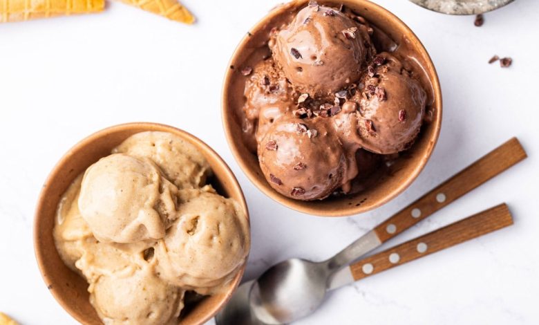 Two bowls of protein ice cream-one is chocolate and one is vanilla. There are two spoons next to the bowls.