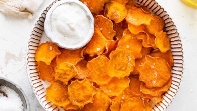 Baked sweet potato chips in a bowl with a small bowl of white dipping sauce.
